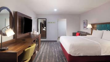 A hotel room with a bed, desk, chair, TV, and a mirror.