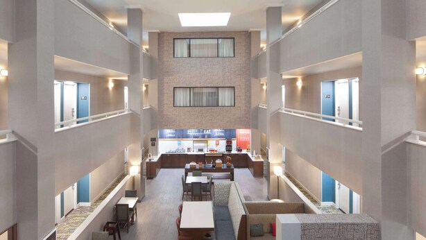 A hotel lobby with a central seating area, a kitchenette, and a staircase leading to upper floors. - Hampton Inn Athens (Athens)