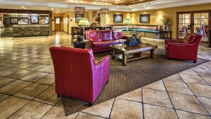 A lobby with a reception desk, red leather sofas, a coffee table, and a patterned rug.