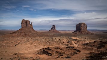 Un extenso paisaje desértico con tres formaciones rocosas destacadas.