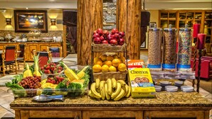 A breakfast buffet with fresh fruits, vegetables, and cereals.