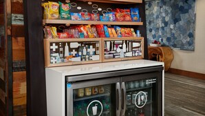 Eine Speisenauslage mit verschiedenen Chips und ein Kühlschrank mit Getränken.