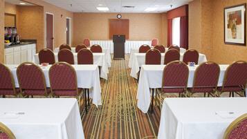 A conference room with multiple tables and chairs, a podium, and a clock on the wall.