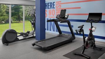 Une salle de sport équipée d’un tapis de course, d’un vélo elliptique et d’un vélo d’appartement, dotée de grandes fenêtres et d’un mur décoré de citations motivantes.