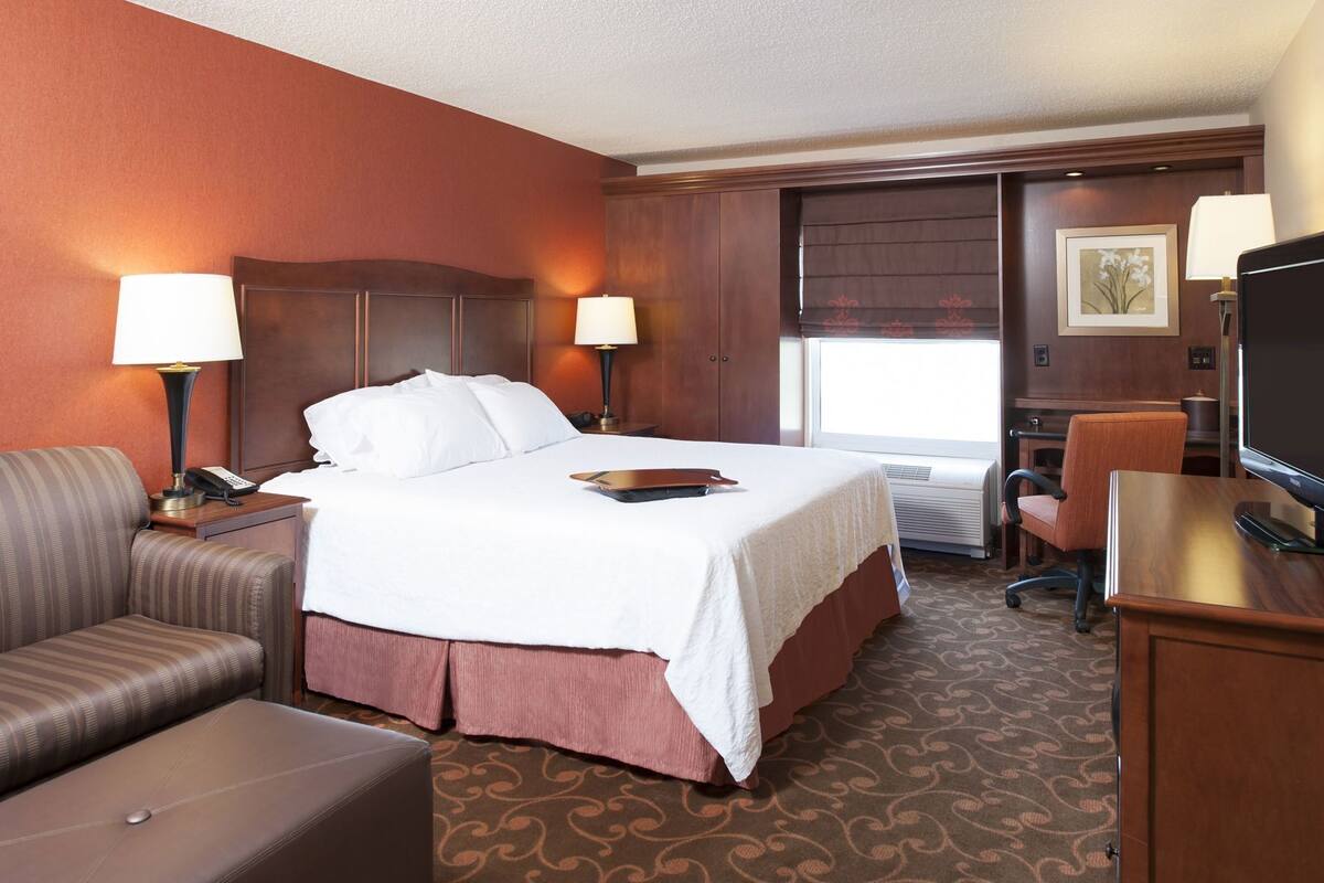 Une chambre d’hôtel comprenant un lit, un bureau, une chaise, un canapé et un téléviseur.