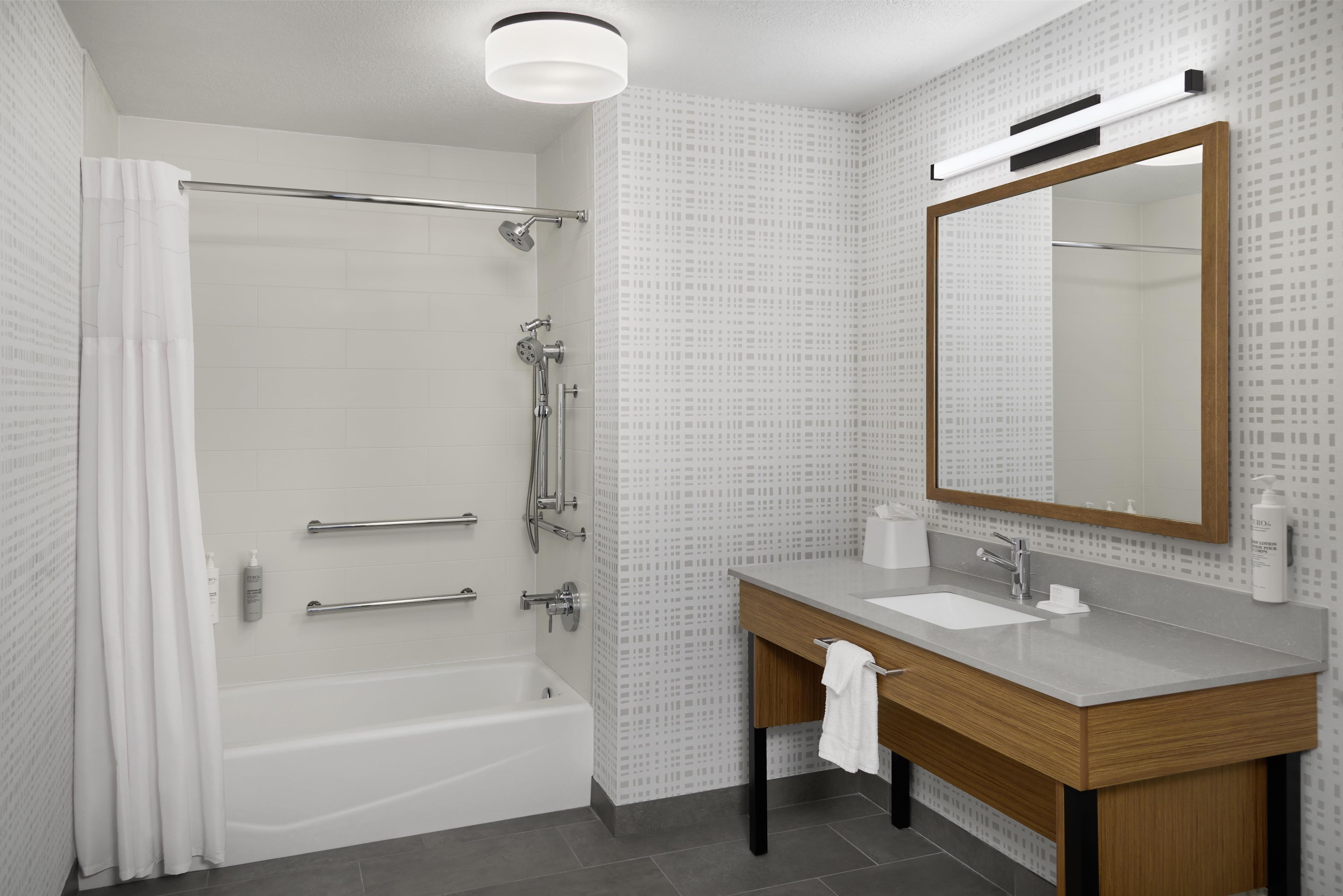 Ein modernes Badezimmer mit Badewanne, Dusche, Waschtisch und einem großen Spiegel.