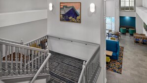 A multi-level interior with a staircase, seating area, and artwork on the wall.