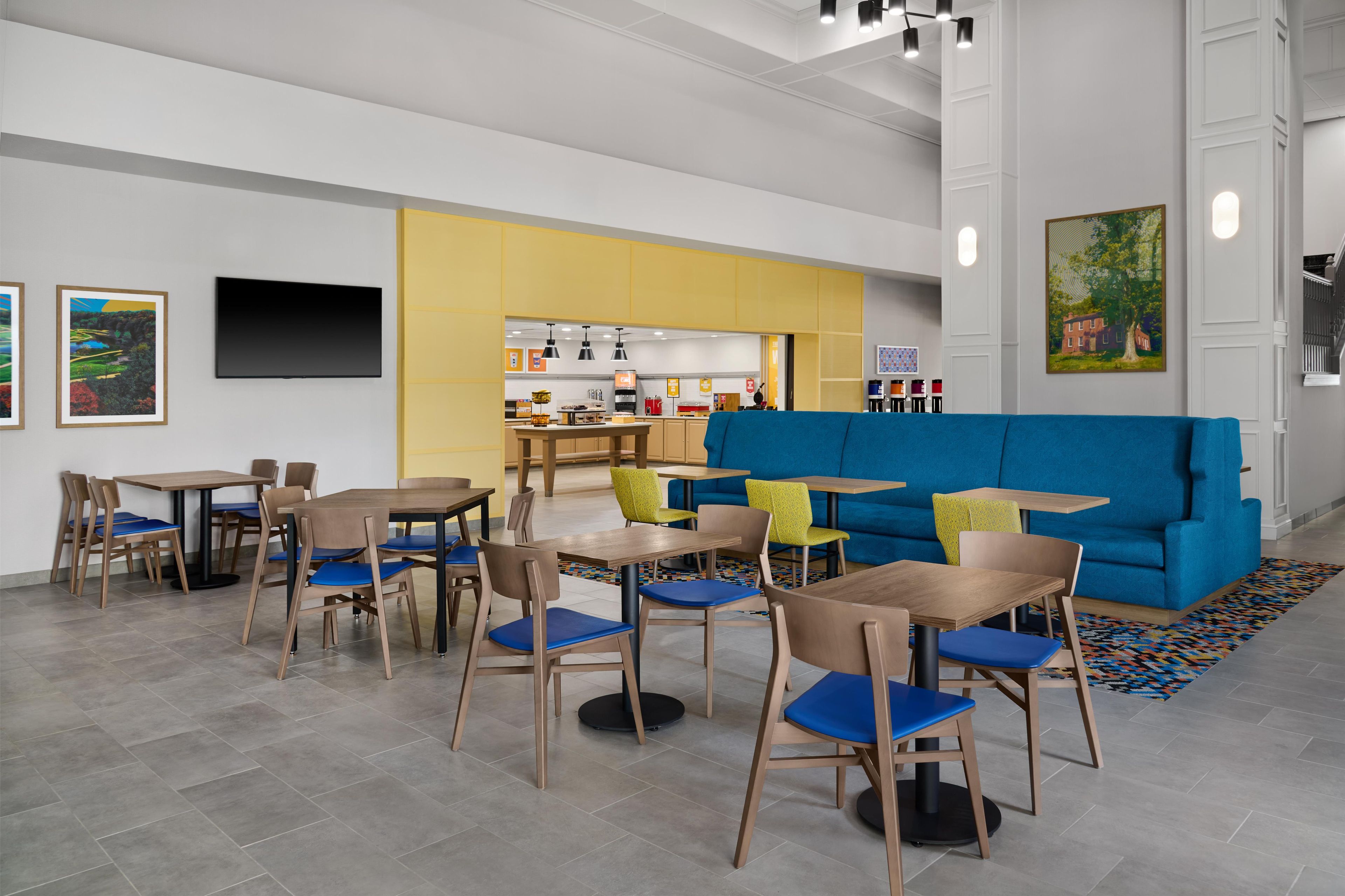 Ein modernes Interieur mit Tischen, Stühlen, einer Küchenzeile und einem blauen Sofa.