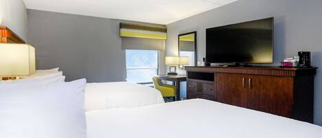 A hotel room with two beds, a desk with a chair, a television, and a minibar.