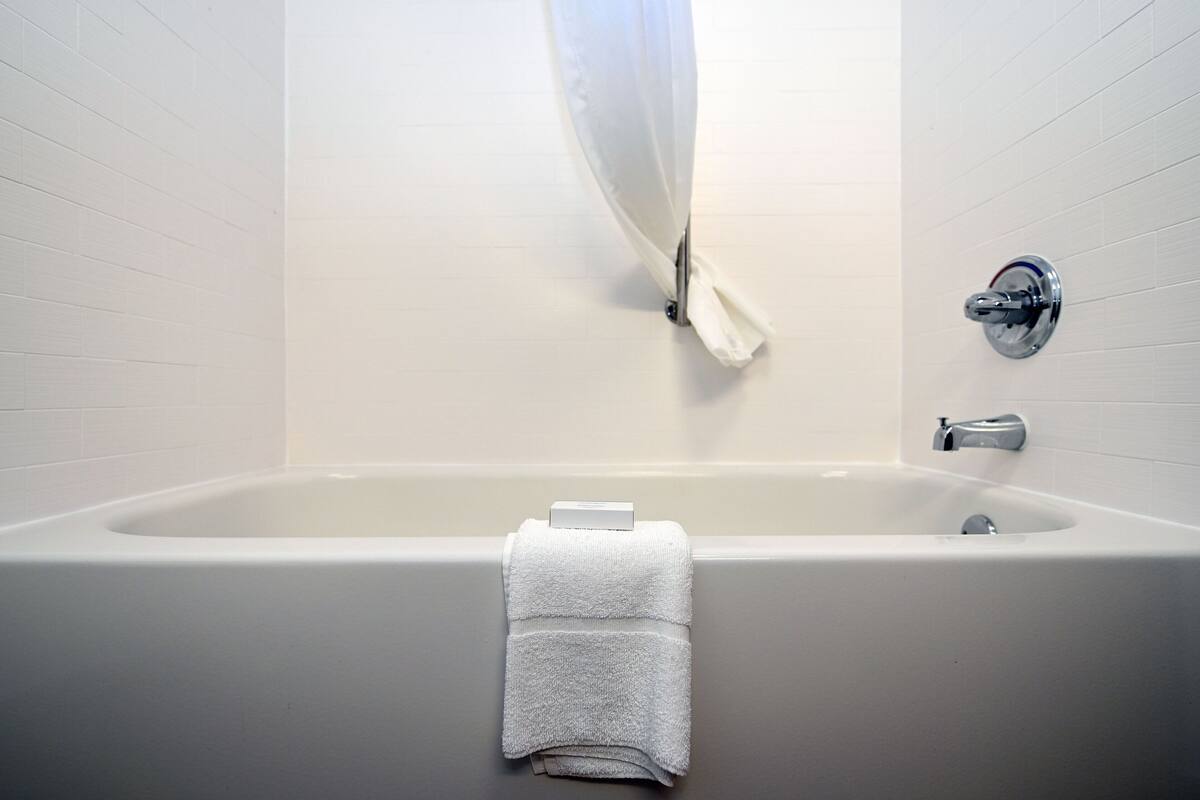 A bathroom with a bathtub, a towel, and a shower curtain.