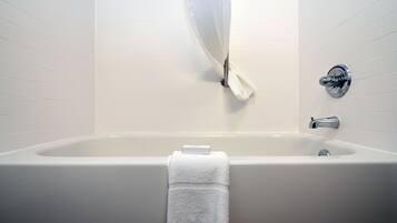 A bathroom with a bathtub, a towel, and a shower curtain.
