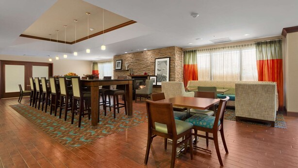 A hotel lobby with a dining area, seating, a fireplace, and a view of the outside through large windows. - Hampton Inn by Hilton Lexington Park (Lexington Park)