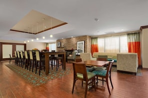 A hotel lobby with a dining area, seating, a fireplace, and a view of the outside through large windows. - Hampton Inn by Hilton Lexington Park (Lexington Park)