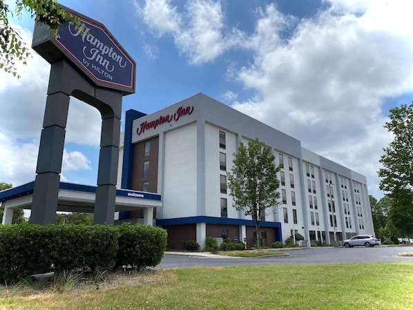 A Hampton Inn hotel with a large sign, a modern building facade, and a parking lot. - Hampton Inn by Hilton Lexington Park (Lexington Park)