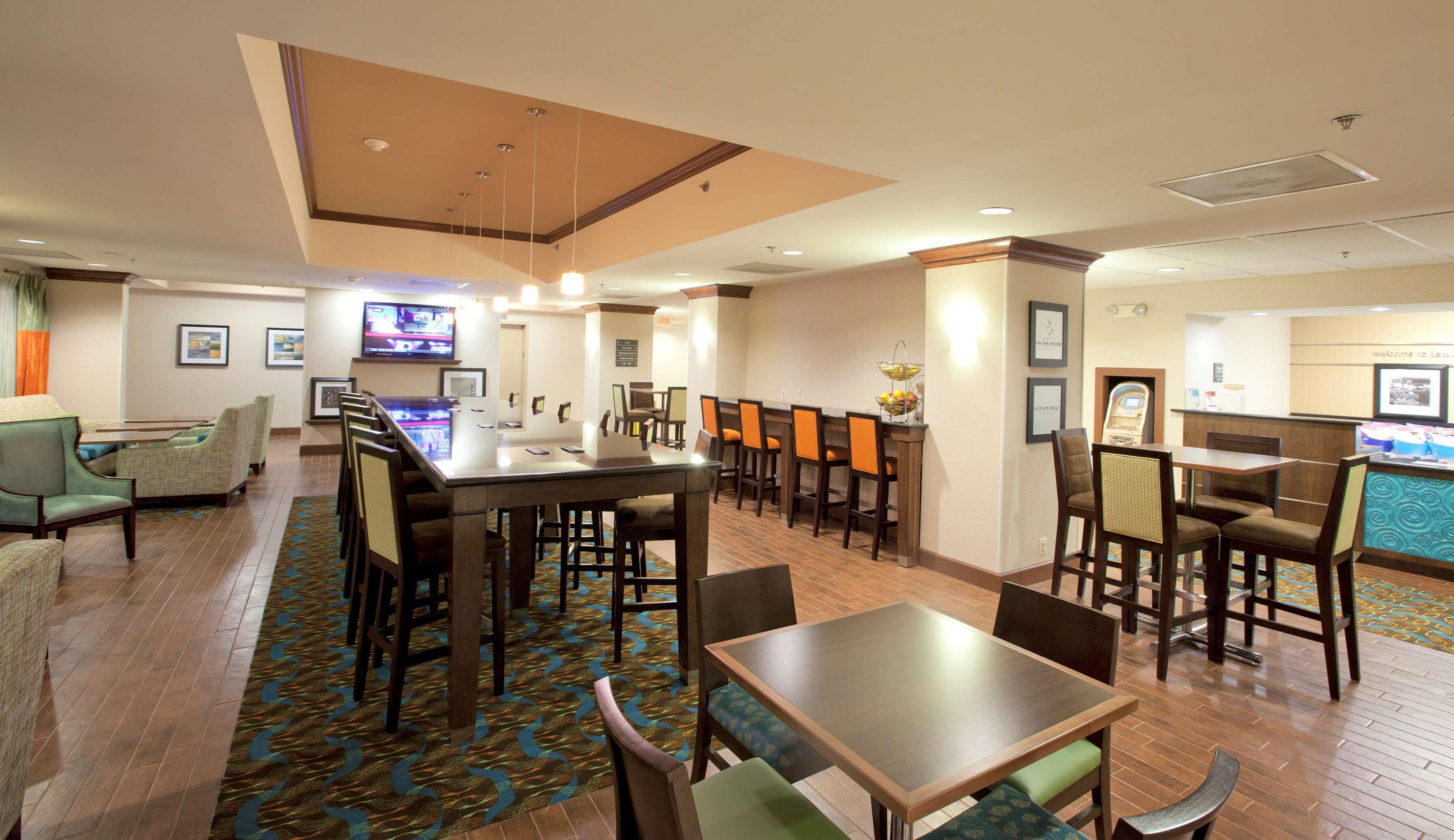 A hotel lobby with a reception desk, seating area, and a bar.