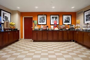 A spacious kitchen with a checkered floor, wooden cabinets, and various breakfast items on the counter. - Hampton Inn by Hilton Lexington Park (Lexington Park)