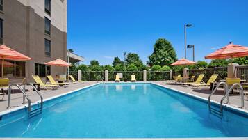 Relax by the rectangular pool surrounded by lounge chairs and umbrellas.