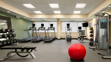 A gym with treadmills, weight machines, and exercise balls.