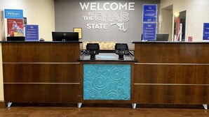 A reception desk with a 'Welcome to the Crab State' sign, two HP laptops, and a 'No Mask, No Service' sign. - Hampton Inn by Hilton Lexington Park (Lexington Park)