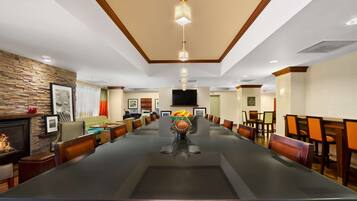 A conference room with a long table, chairs, a fireplace, and a television on the wall.