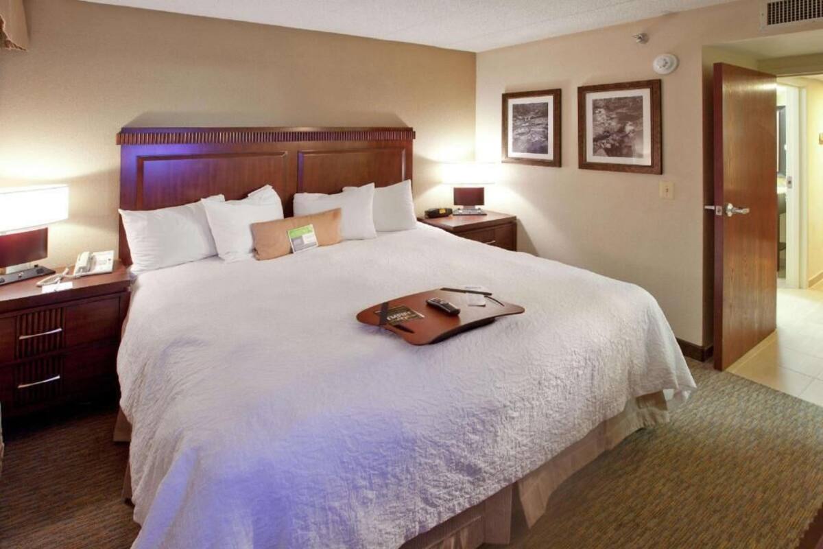 A hotel room with a large bed, bedside tables, a nightstand, a lamp, and a framed picture on the wall.