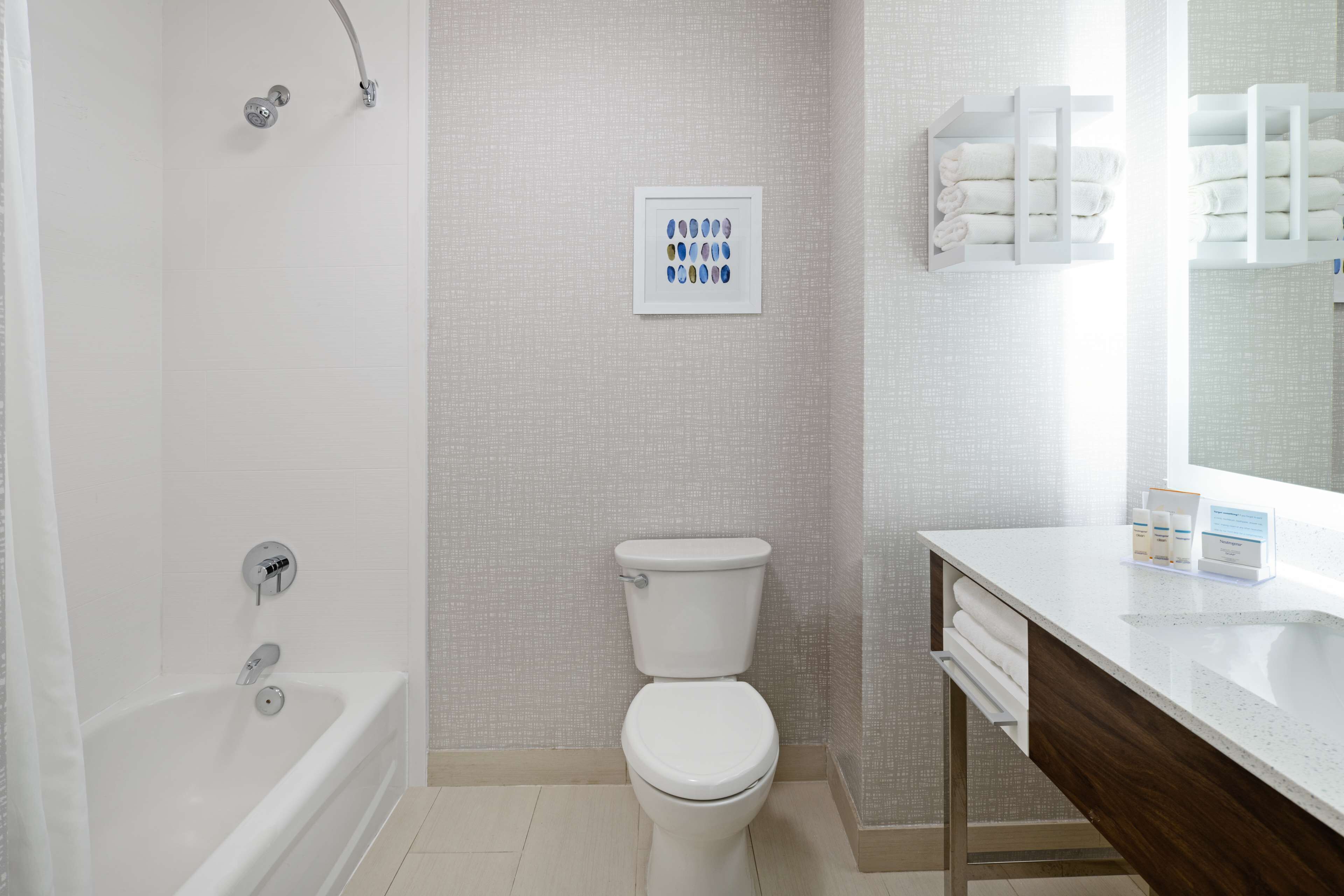 A modern bathroom with a bathtub, toilet, and a vanity with a mirror.