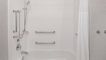 Une salle de bain moderne équipée d’une baignoire, de barres d’appui et d’un pommeau de douche.