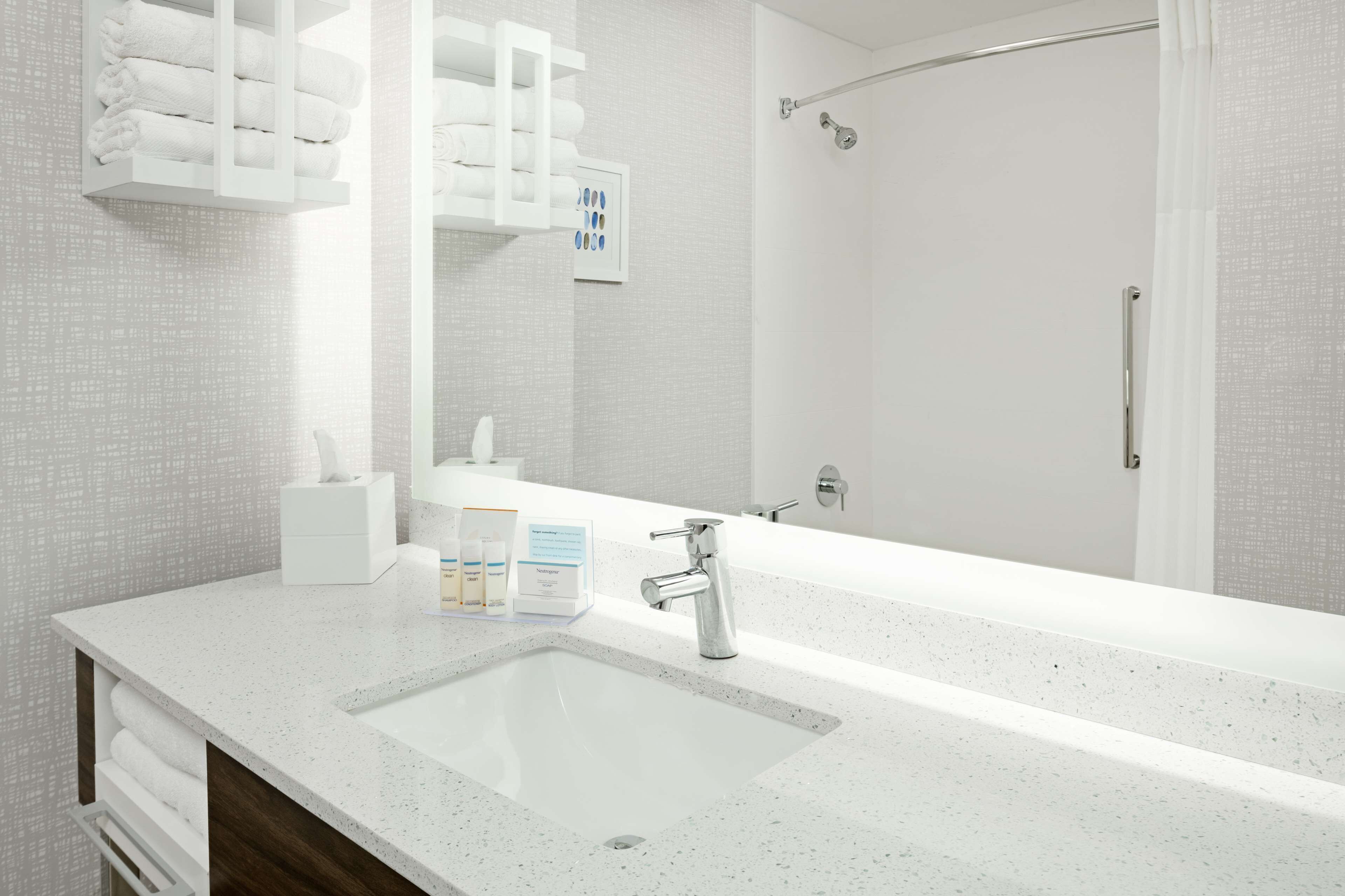A modern bathroom with a large mirror, a sink, and a shower area.