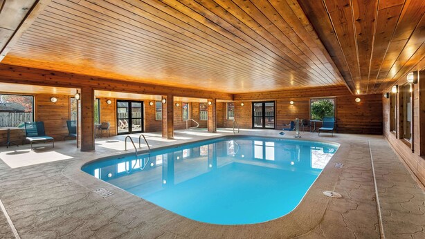 An indoor swimming pool with wooden walls and ceiling, surrounded by lounge chairs and a stone floor. - Hampton Inn Marion (Marion)