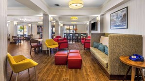 A spacious lobby with a wooden floor, red and yellow chairs, a sofa, and a blue telephone. - Hampton Inn Marion (Marion)