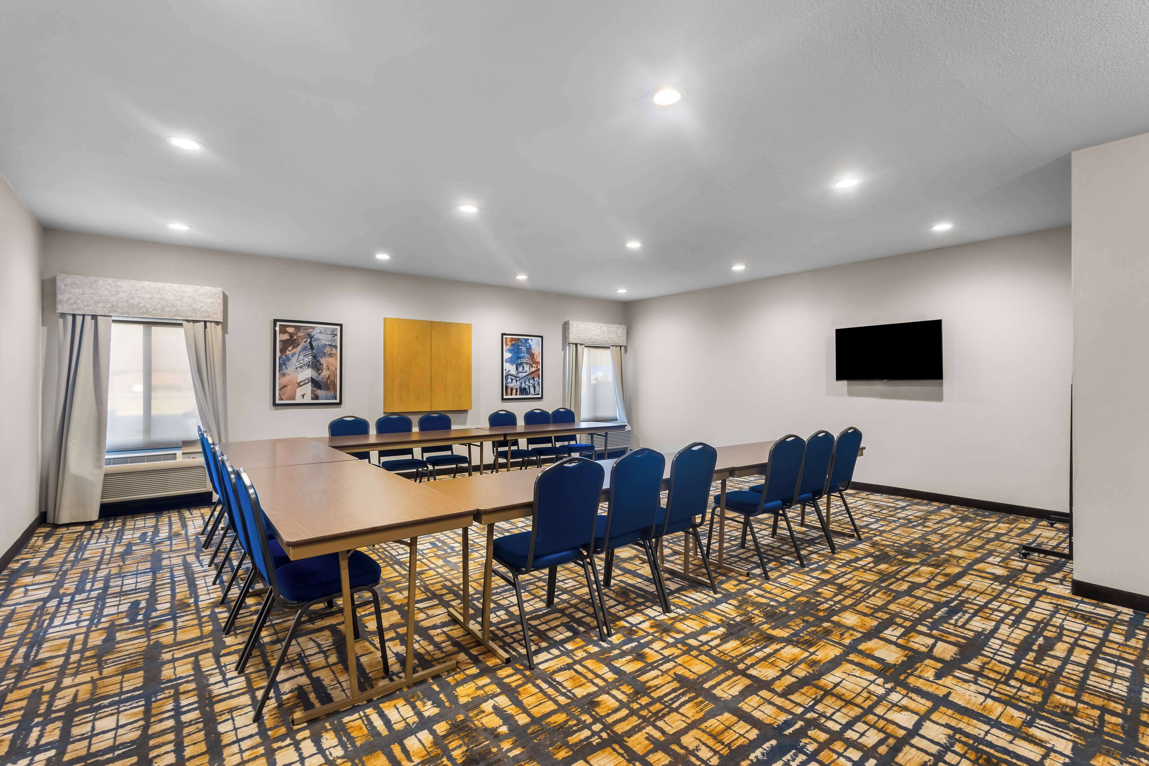 A conference room with a long table, blue chairs, and a patterned carpet.