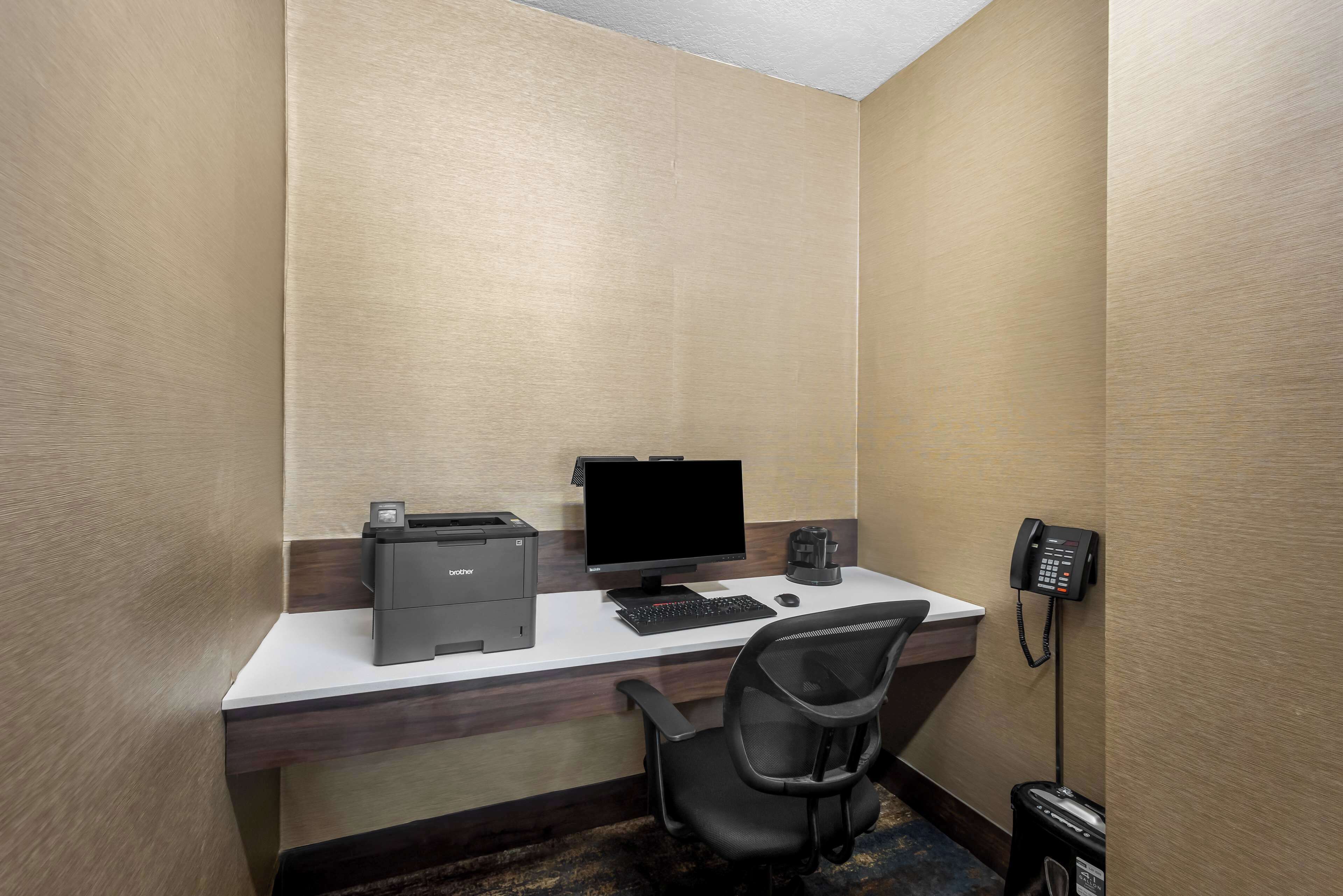 Un bureau d’hôtel équipé d’un bureau, d’un ordinateur, d’une imprimante et d’un téléphone.