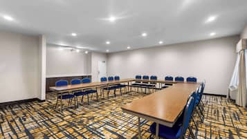 A conference room with a long table, blue chairs, and patterned carpet.