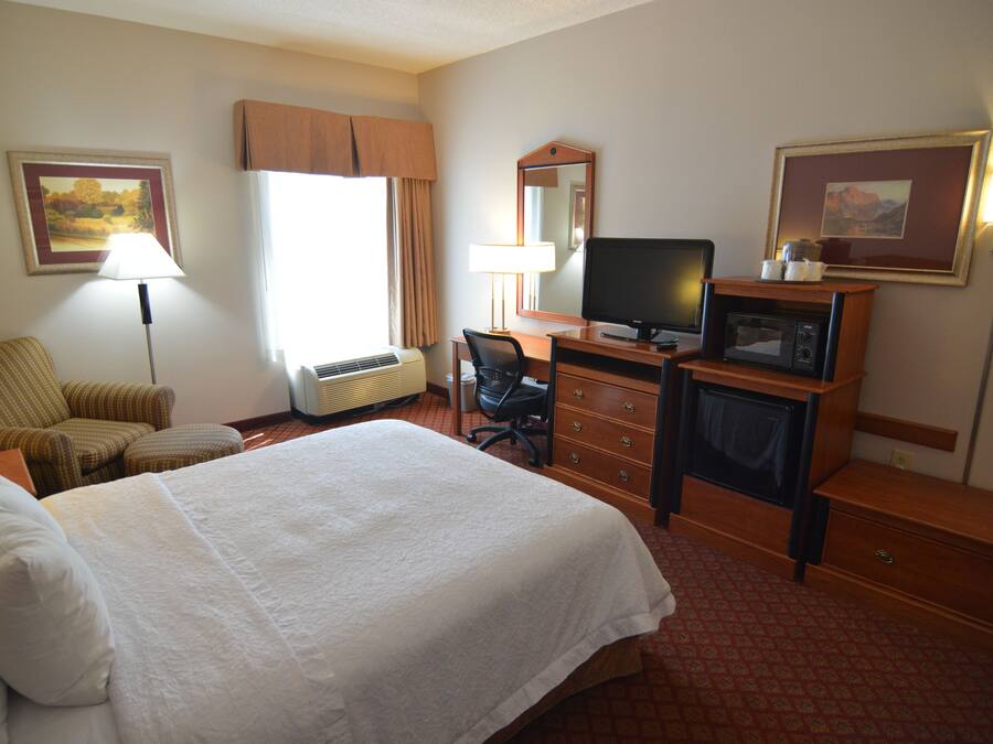 Une chambre d’hôtel équipée d’un lit, d’un bureau, d’une chaise, d’une télévision, d’un four à micro-ondes et d’une lampe.