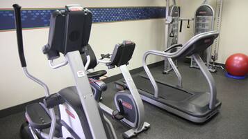 A gym with cardio machines, a weight machine, and a red exercise ball.