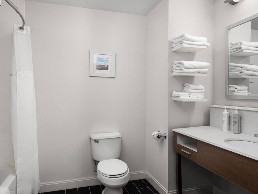 A bathroom with a toilet, a sink, a mirror, and a towel rack.