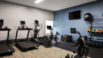 A gym with treadmills, an elliptical, a stationary bike, and a rack of exercise balls.