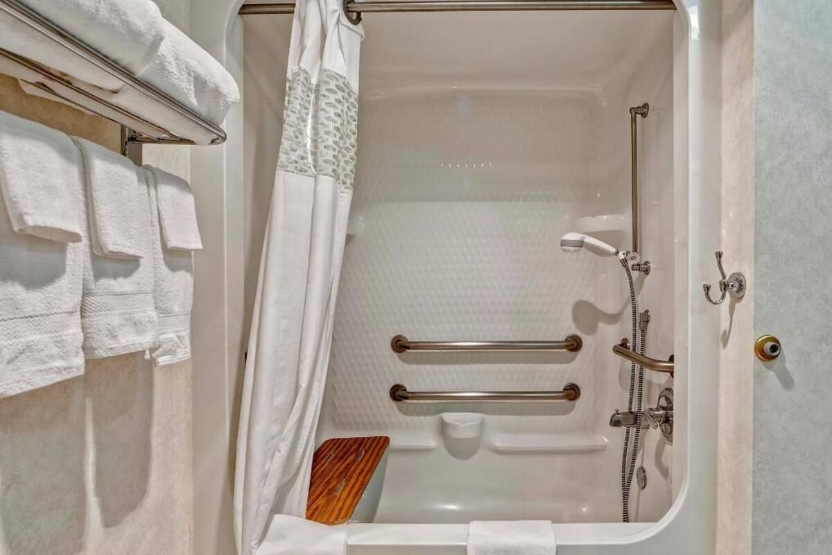 A bathroom with a bathtub, towel rack, and shower.