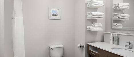 A modern bathroom with a toilet, a shower, a sink, and a towel rack.