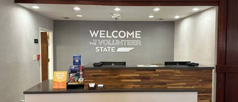 A reception desk with a "WELCOME THE VOLUNTEER STATE" sign, a wooden counter, and a wall-mounted light fixture.