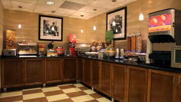 Una cocina con armarios de madera, piso a cuadros, una cafetera y un dispensador de jugo.
