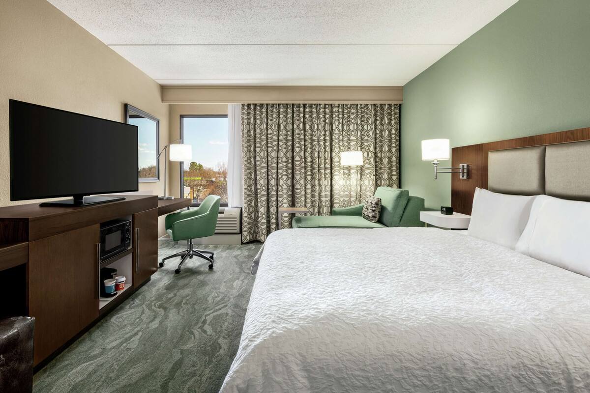 Une chambre d’hôtel avec un grand lit, une télévision, un bureau et une chaise.