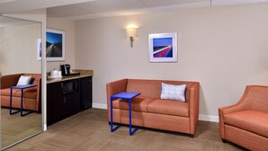 Une chambre d’hôtel avec un canapé, une petite table, une machine à café et un miroir.