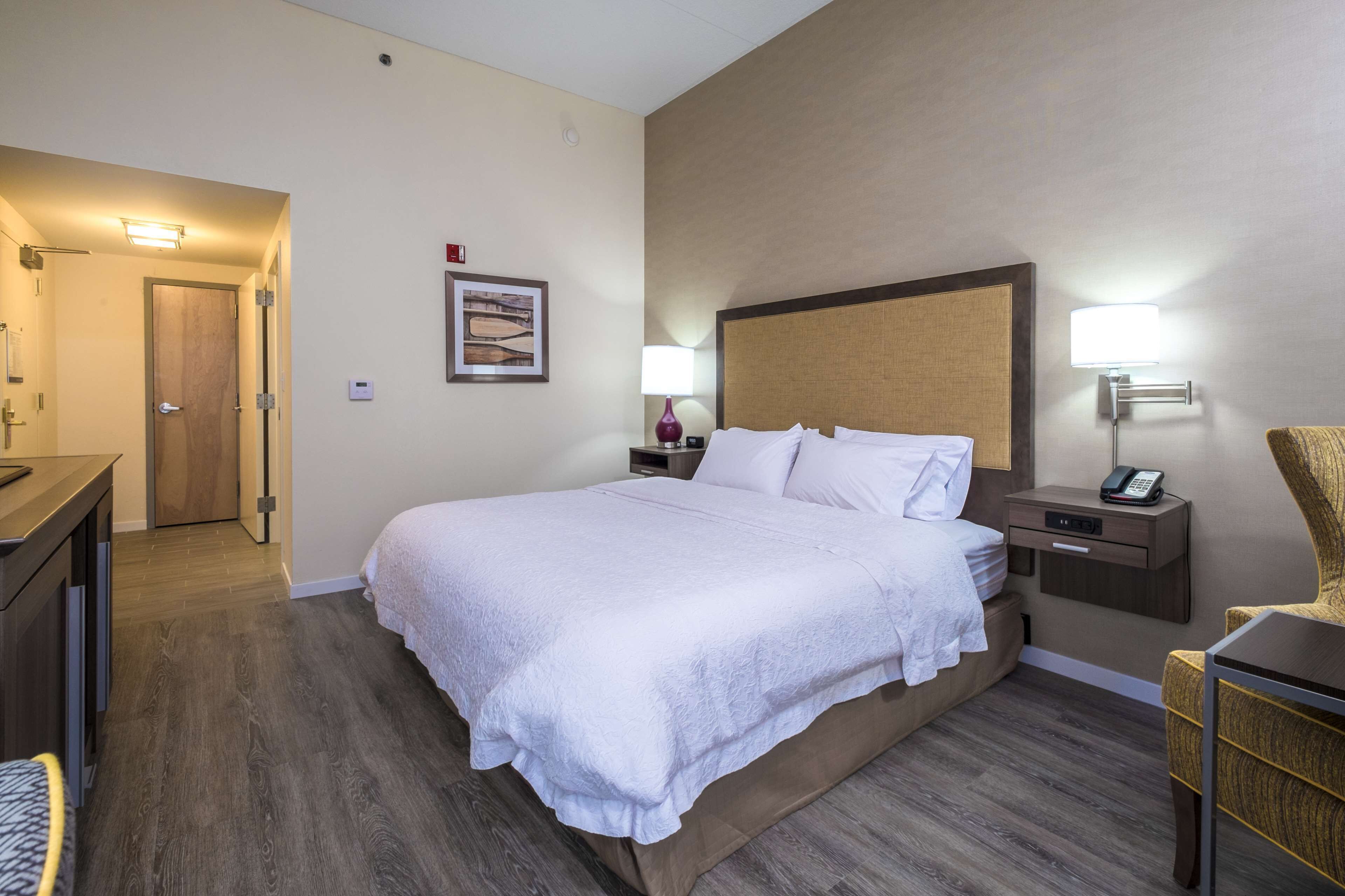 A hotel room with a large bed, bedside tables, a desk, and a chair.