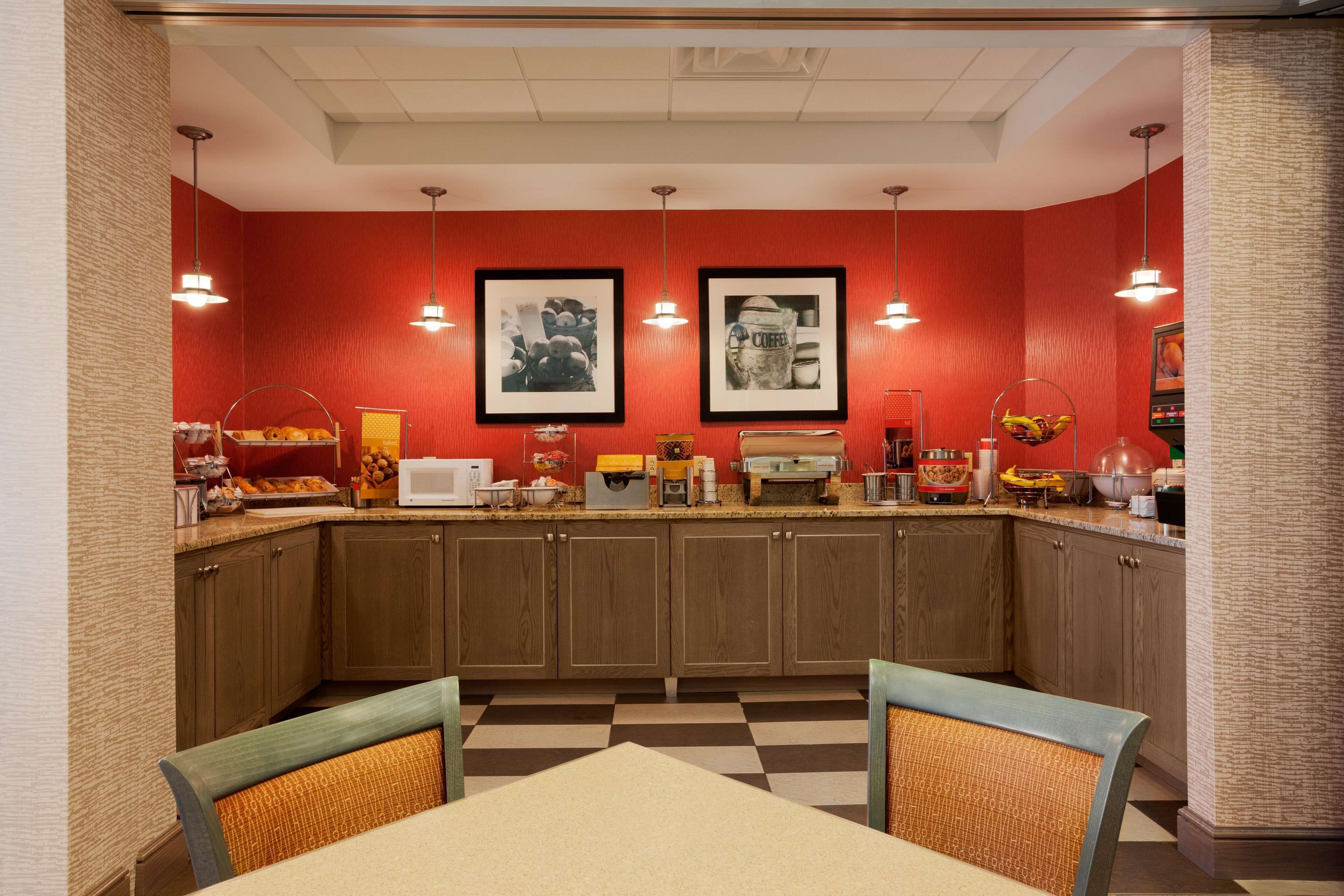 A kitchen with wooden cabinets, a checkered floor, and a dining area with a table and chairs.