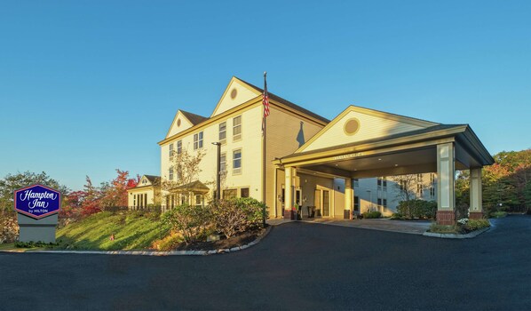 Um Hampton Inn by Hilton com entrada coberta e um mastro com bandeira.