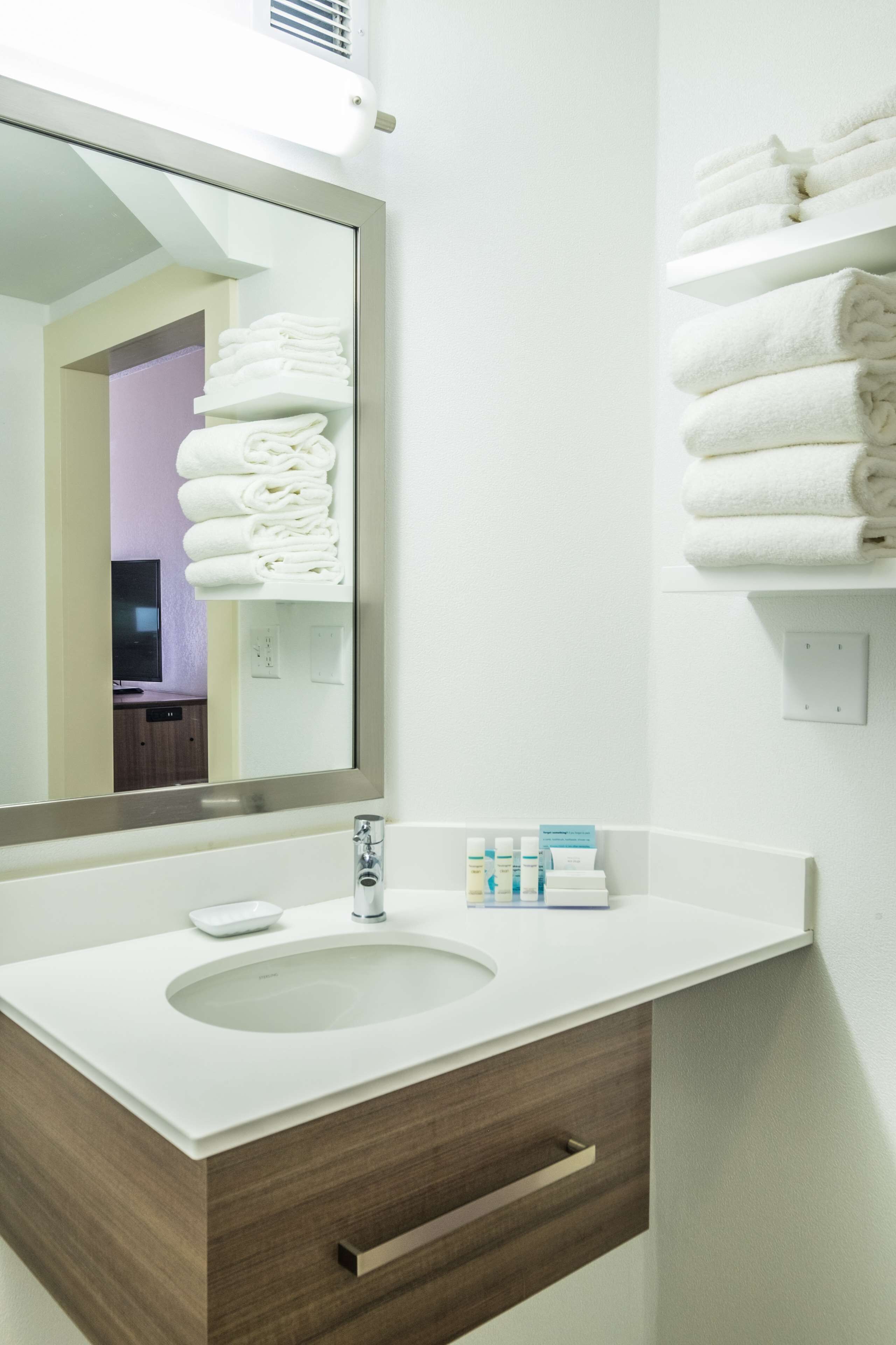 A bathroom with a white sink, a mirror, and a towel rack.
