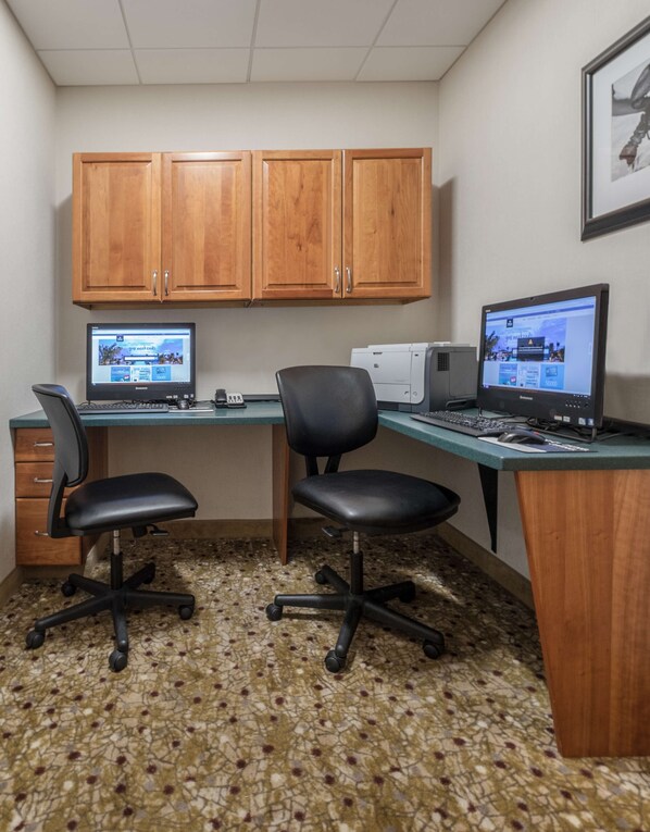 A small office with two desks, two chairs, a printer, and wooden cabinets.