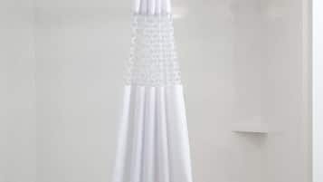 A white bathtub with a shower curtain, a handheld showerhead, and a wall-mounted faucet.