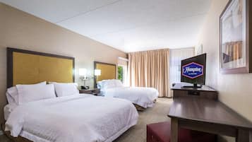 Habitación de hotel con dos camas, un escritorio, televisor y un cuadro en la pared.